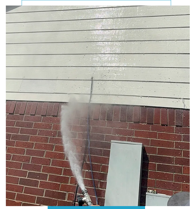 Water spraying forcefully from a pipe outside a building.