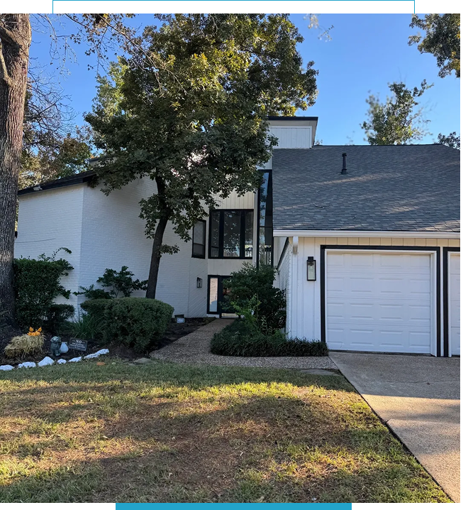 White suburban house with a garage and a small front garden under clear blue sky.